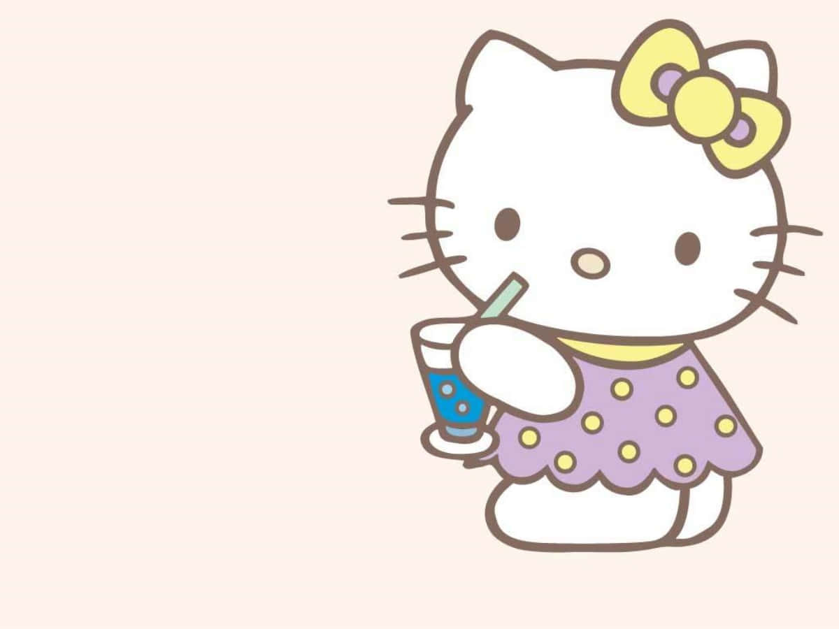 Hello Kitty שותה משקה ליד מחשב נייד טפט