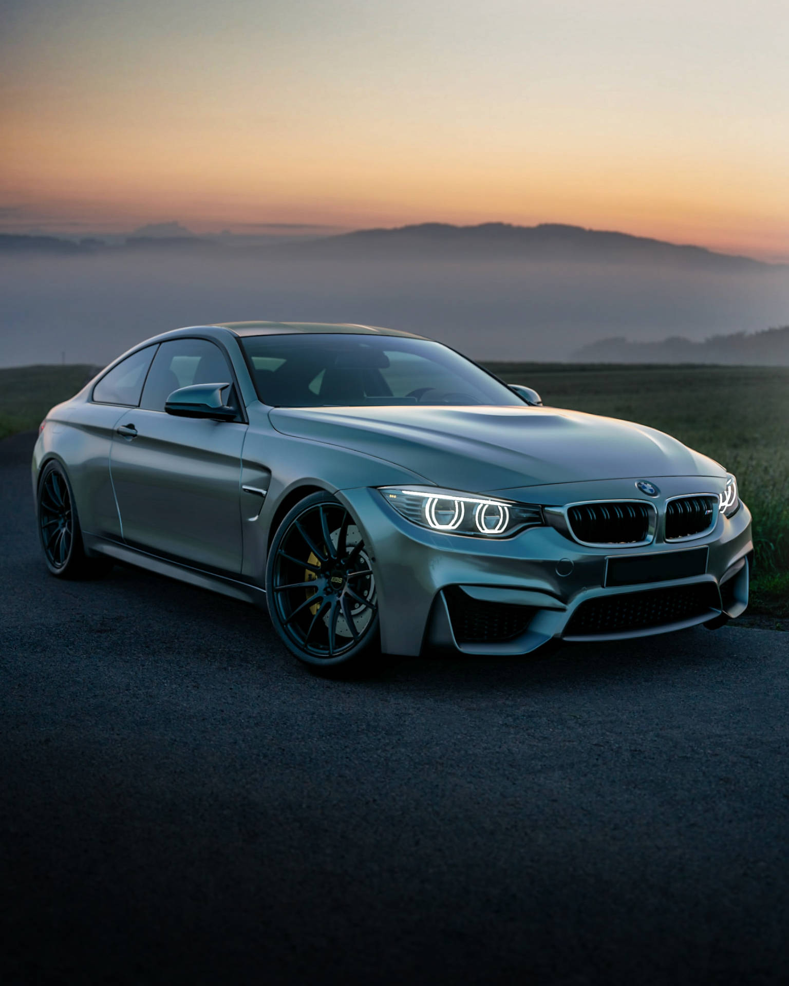 טפט של מכונית BMW F83 M4 אפורה על הר בזריחה