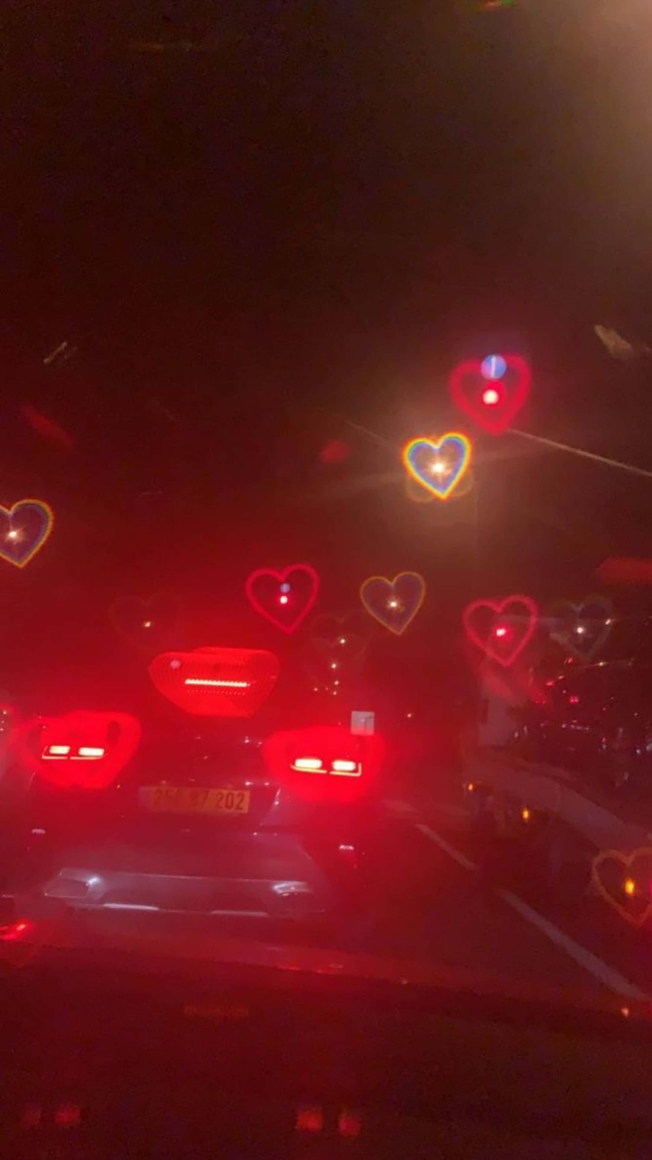 מכונית נוסעת בכביש בלילה עם לבבות על השמשה טפט