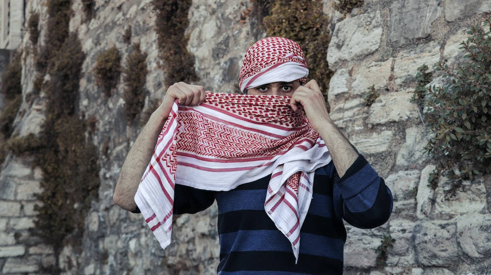 נער מוסלמי בצעיף משובץ אדום טפט