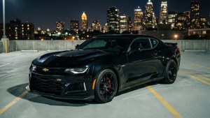 טפט קמארו ZL1 שחורה חונה בחניון על גג עם קו הרקיע של העיר בלילה.